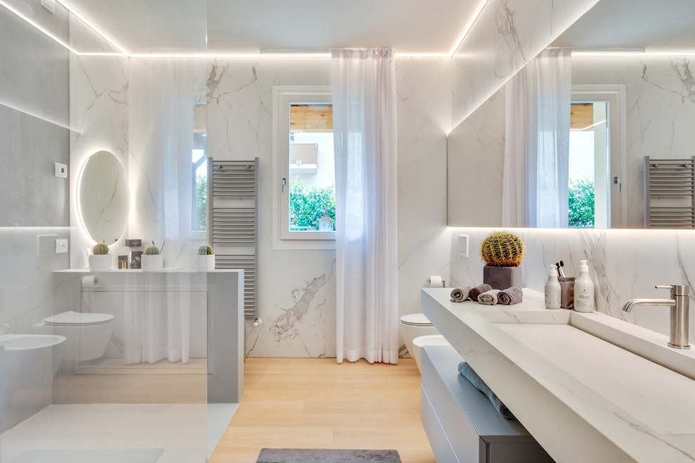 Design ideas for a large modern master bathroom in Other with flat-panel cabinets, grey cabinets, an open shower, a wall-mount toilet, white tile, porcelain tile, white walls, painted wood floors, a trough sink, white benchtops, an enclosed toilet, a single vanity and a floating vanity.