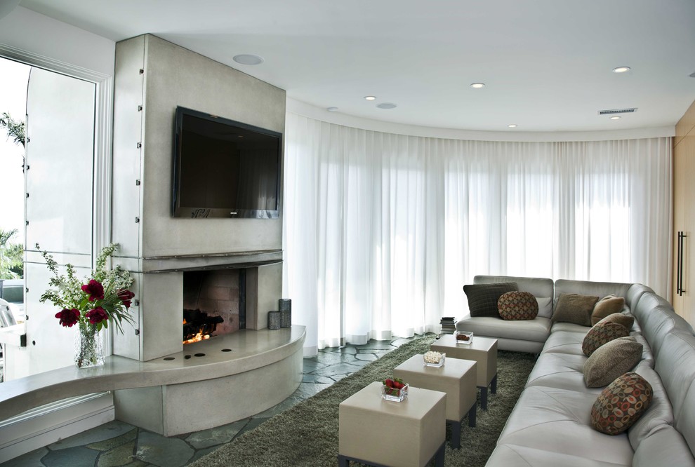 Photo of a large beach style enclosed family room in San Diego with a home bar, white walls, slate floors, a two-sided fireplace, a concrete fireplace surround and a wall-mounted tv.