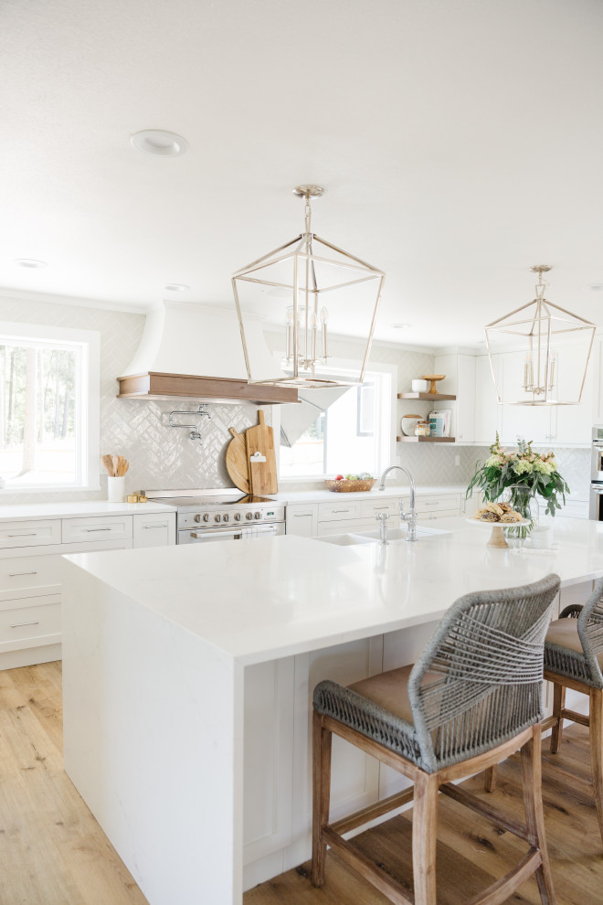 Large transitional u-shaped open plan kitchen in Other with a farmhouse sink, shaker cabinets, white cabinets, quartzite benchtops, white splashback, porcelain splashback, stainless steel appliances, light hardwood floors, with island, beige floor and white benchtop.