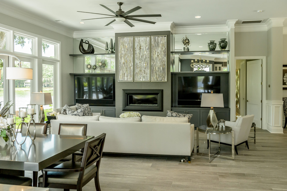 Design ideas for a mid-sized contemporary open concept family room in Charleston with grey walls, porcelain floors, a standard fireplace, a built-in media wall, brown floor and a plaster fireplace surround.