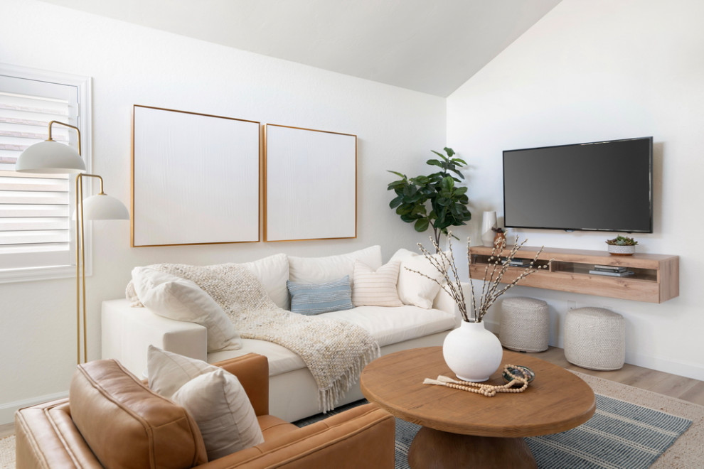 Immagine di un soggiorno stile marinaro aperto e di medie dimensioni con pareti bianche, pavimento in laminato, TV a parete, pavimento beige e soffitto a volta