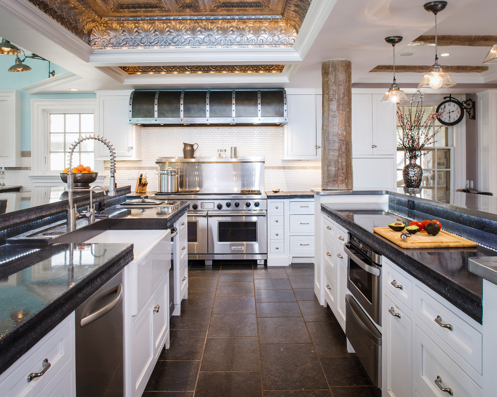 Traditional u-shaped kitchen in New York with a farmhouse sink, shaker cabinets, white cabinets, white splashback, subway tile splashback, stainless steel appliances, multiple islands and black benchtop.