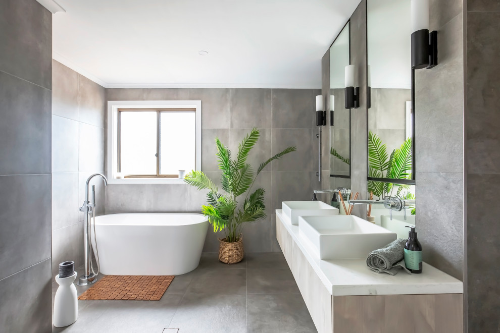 This is an example of a large contemporary wet room bathroom in Sydney with beige cabinets, a freestanding tub, a one-piece toilet, gray tile, grey walls, grey floor, an open shower, white benchtops, a double vanity and a floating vanity.