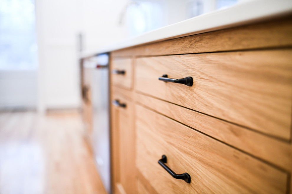 Example of a mid-sized transitional single-wall dark wood floor and brown floor enclosed kitchen design in Boston with an undermount sink, shaker cabinets, white cabinets, quartz countertops, white backsplash, subway tile backsplash, stainless steel appliances and an island