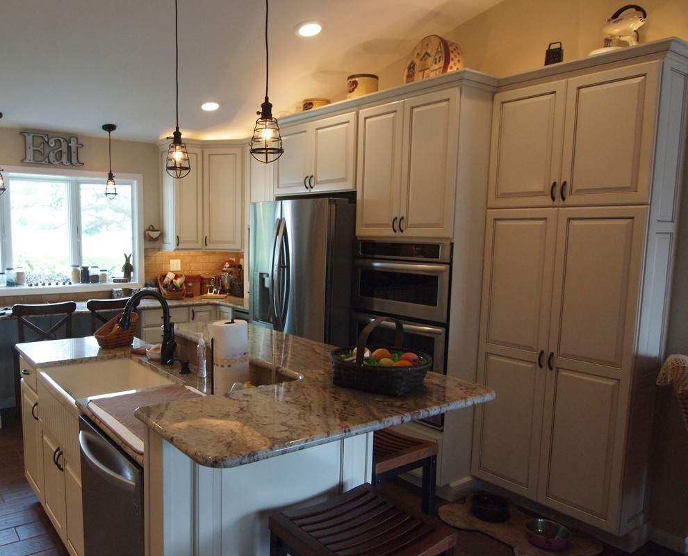 Mid-sized elegant u-shaped ceramic tile enclosed kitchen photo in Baltimore with a farmhouse sink, raised-panel cabinets, white cabinets, granite countertops, beige backsplash, stone tile backsplash, stainless steel appliances and an island