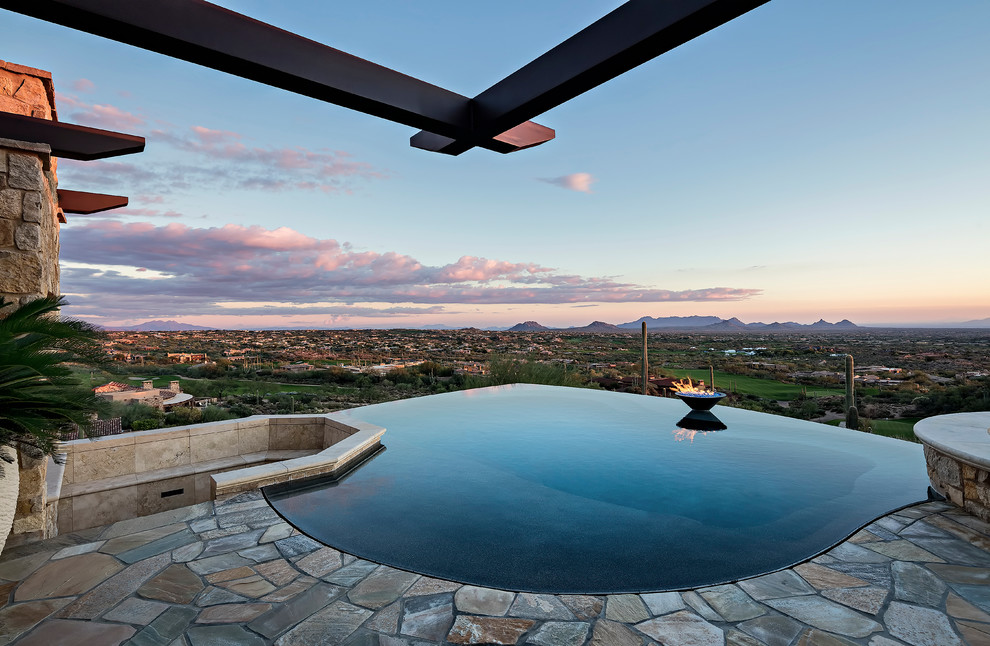 Photo of a custom-shaped infinity pool in Phoenix with natural stone pavers.