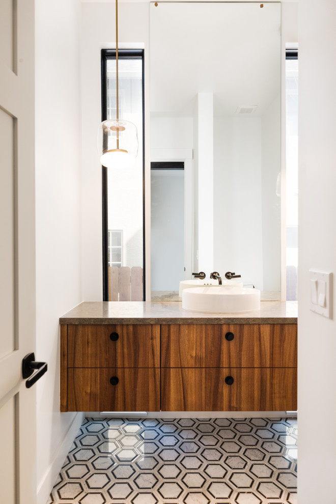 Design ideas for a mid-sized modern powder room in Denver with flat-panel cabinets, medium wood cabinets, a one-piece toilet, white walls, mosaic tile floors, a vessel sink, limestone benchtops, multi-coloured floor, grey benchtops and a floating vanity.
