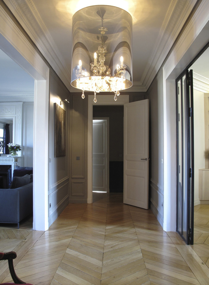 Photo of a mid-sized contemporary hallway in Paris with white walls and light hardwood floors.