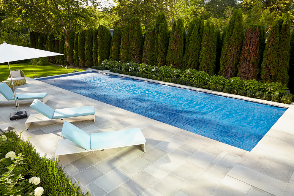 Design ideas for a large transitional backyard rectangular infinity pool in Toronto with a water feature and natural stone pavers.