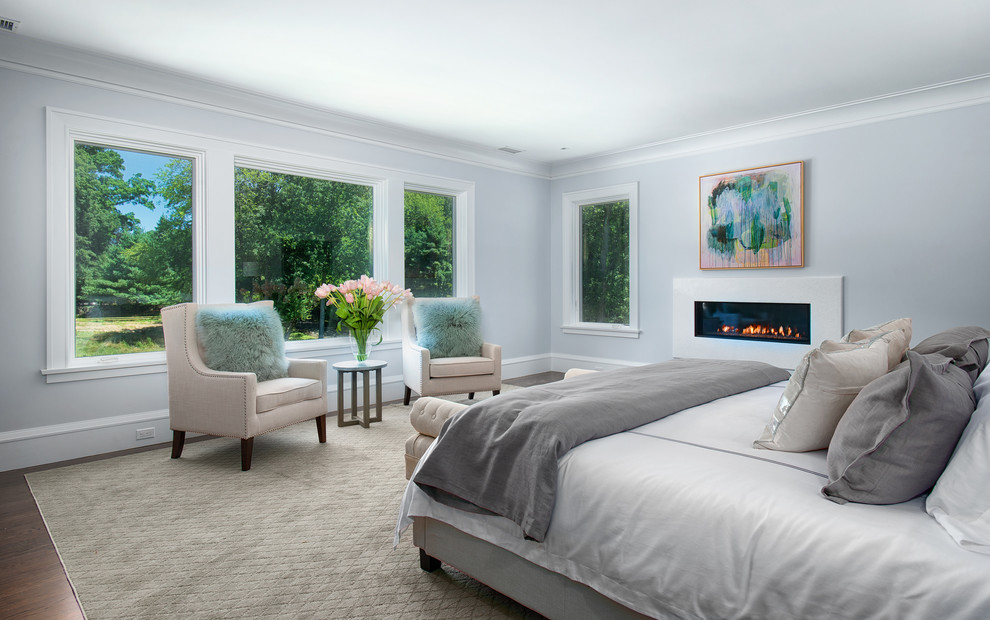 Design ideas for a large transitional master bedroom in New York with grey walls, dark hardwood floors, a ribbon fireplace, a stone fireplace surround and brown floor.