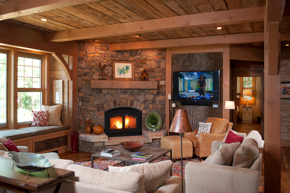 Design ideas for a mid-sized country enclosed living room in Other with brown walls, medium hardwood floors, a standard fireplace, a stone fireplace surround and a wall-mounted tv.