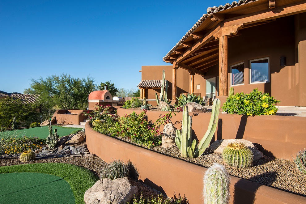 Large backyard garden in Phoenix with a retaining wall and natural stone pavers.