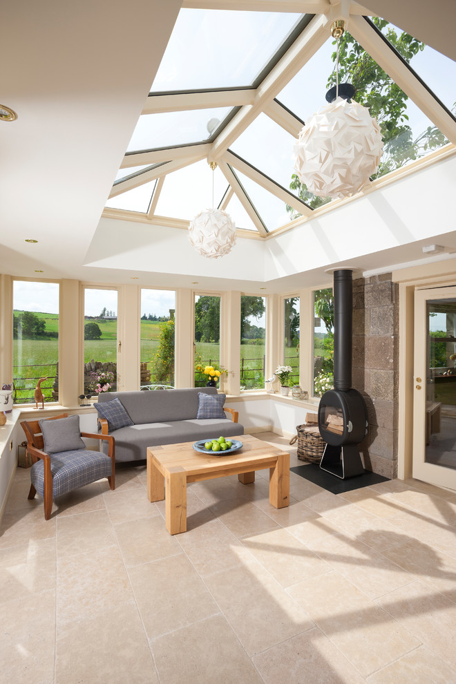 Photo of a large traditional sunroom in Edinburgh with travertine floors, a wood stove, a plaster fireplace surround, a skylight and beige floor.