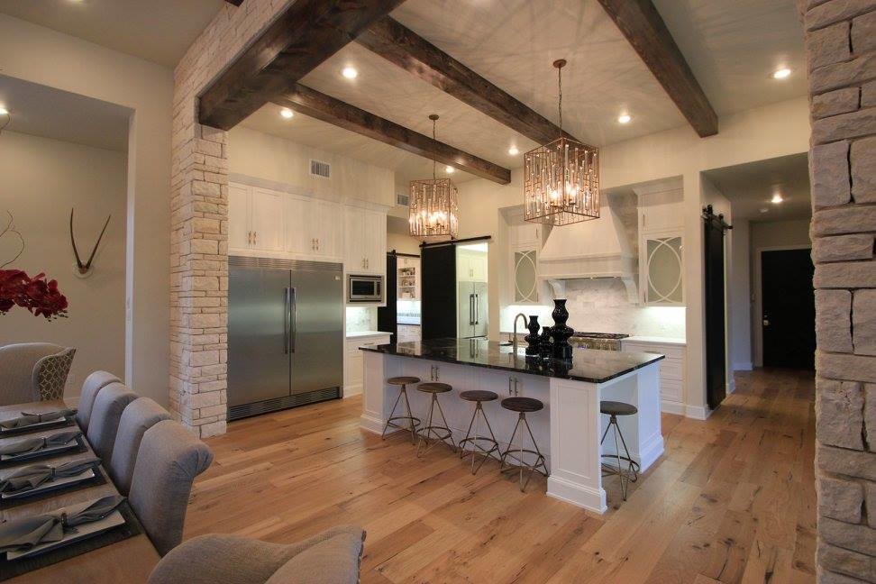Transitional u-shaped open plan kitchen in Austin with a farmhouse sink, flat-panel cabinets, white cabinets, marble benchtops, white splashback, subway tile splashback, stainless steel appliances, light hardwood floors and with island.