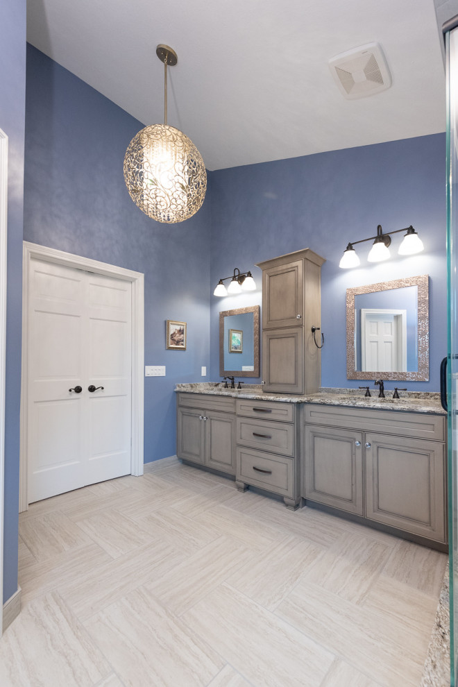 Design ideas for a mid-sized traditional master bathroom in Indianapolis with beaded inset cabinets, grey cabinets, a corner shower, white tile, glass sheet wall, blue walls, ceramic floors, an undermount sink, granite benchtops, a hinged shower door, multi-coloured benchtops, a double vanity and a built-in vanity.