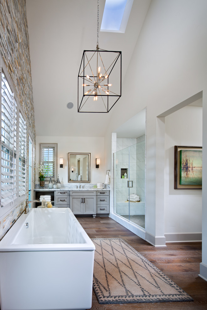 Inspiration for a large transitional master bathroom in San Diego with recessed-panel cabinets, grey cabinets, a freestanding tub, an alcove shower, white walls, marble benchtops, medium hardwood floors and a hinged shower door.