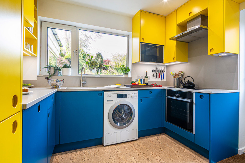 Small contemporary u-shaped separate kitchen in Other with flat-panel cabinets, yellow cabinets, quartzite benchtops, grey splashback, engineered quartz splashback, black appliances, cork floors, no island, beige floor and grey benchtop.