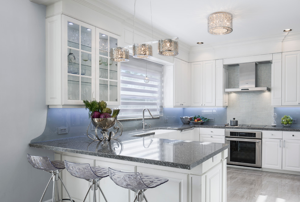 This is an example of a mid-sized transitional u-shaped separate kitchen in Miami with a farmhouse sink, raised-panel cabinets, white cabinets, terrazzo benchtops, grey splashback, glass sheet splashback, stainless steel appliances, porcelain floors, a peninsula and grey floor.