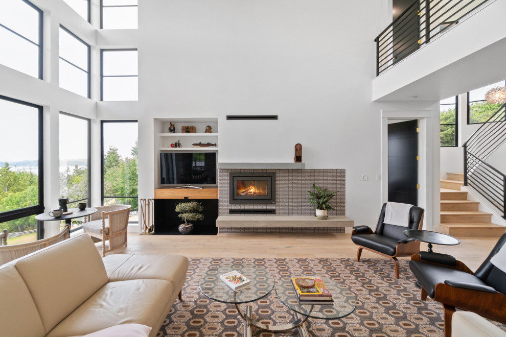 Design ideas for a large modern open plan games room in Seattle with white walls, light hardwood flooring, a standard fireplace, a tiled fireplace surround and a built-in media unit.