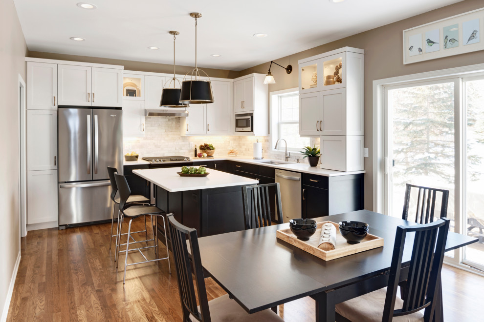 Mid-sized transitional l-shaped medium tone wood floor and brown floor eat-in kitchen photo in Minneapolis with an undermount sink, recessed-panel cabinets, black cabinets, quartz countertops, beige backsplash, stone tile backsplash, stainless steel appliances, an island and white countertops