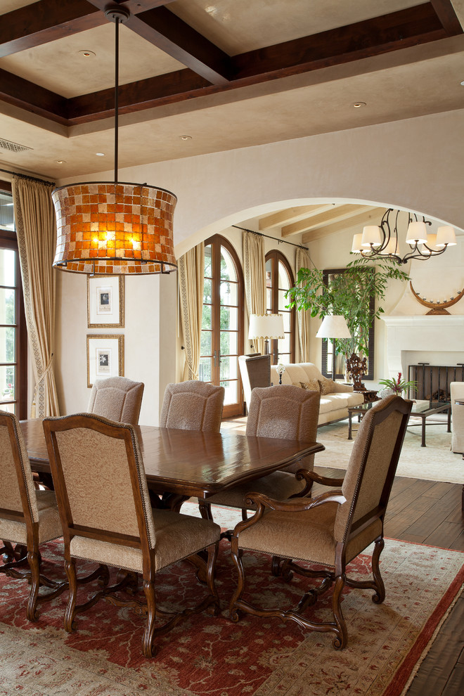 Inspiration for a large mediterranean open plan dining in San Francisco with beige walls, dark hardwood floors, a standard fireplace and a stone fireplace surround.