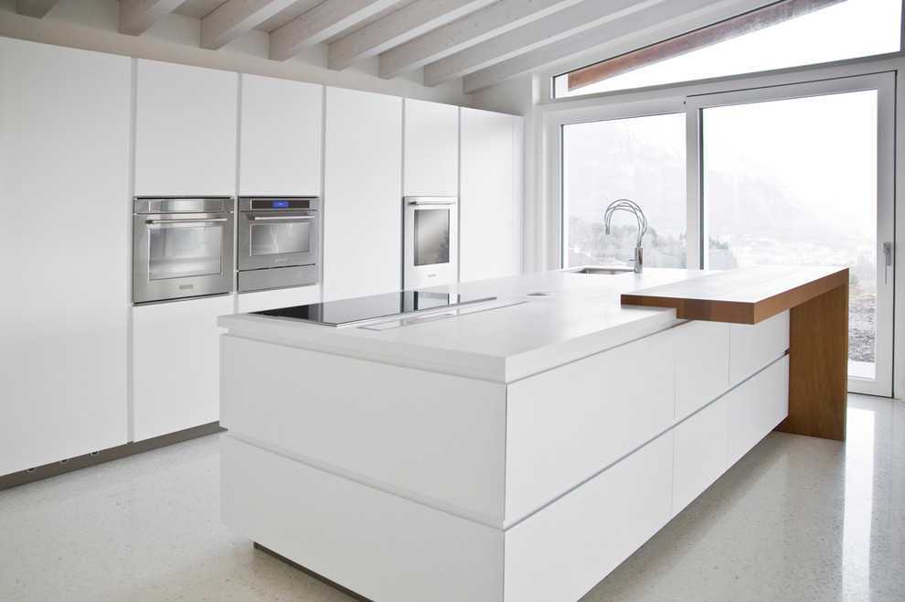 Inspiration for an expansive contemporary eat-in kitchen in Venice with a drop-in sink, flat-panel cabinets, white cabinets, solid surface benchtops, stainless steel appliances and with island.