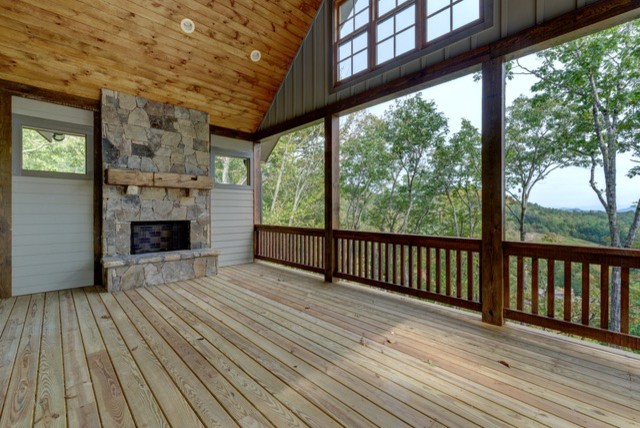 This is an example of a mid-sized country backyard deck in Other with a fire feature and a roof extension.