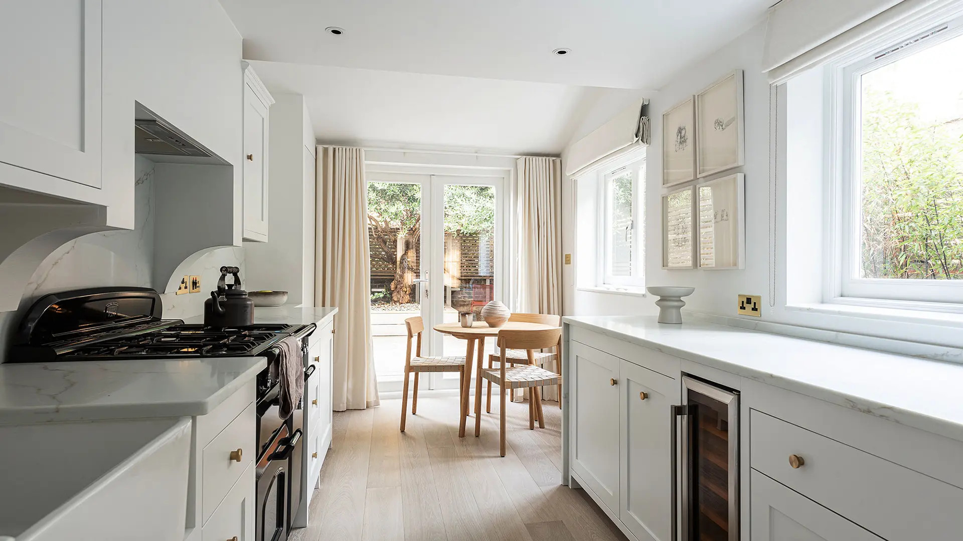The kitchen at House CN by SASI Studio is a bright, calm and elegant space designed around natural light, soft neutral tones and a strong connection to the garden. White cabinetry, marble-style workto