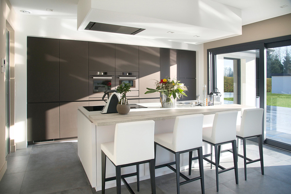 Large contemporary kitchen in Lille with flat-panel cabinets, brown cabinets, coloured appliances, with island and wood benchtops.