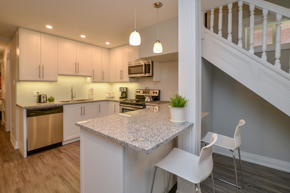 Inspiration for a mid-sized transitional u-shaped medium tone wood floor and gray floor open concept kitchen remodel with an undermount sink, shaker cabinets, white cabinets, granite countertops, stainless steel appliances and a peninsula