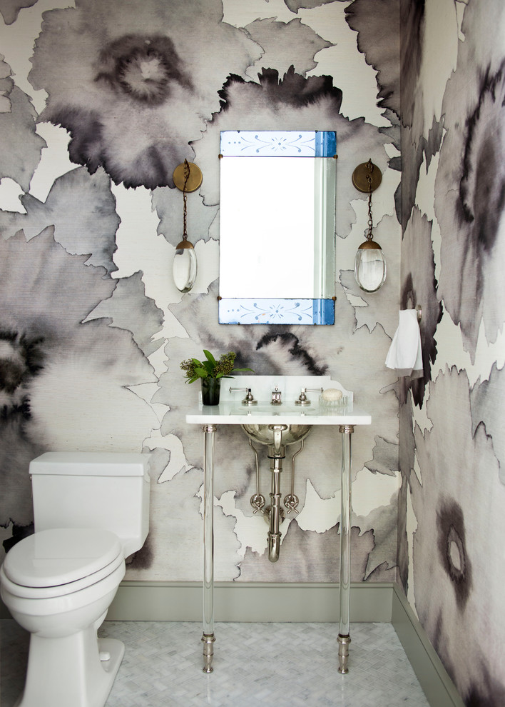 This is an example of a transitional powder room in Atlanta with a one-piece toilet, multi-coloured walls, marble floors, a console sink and white floor.
