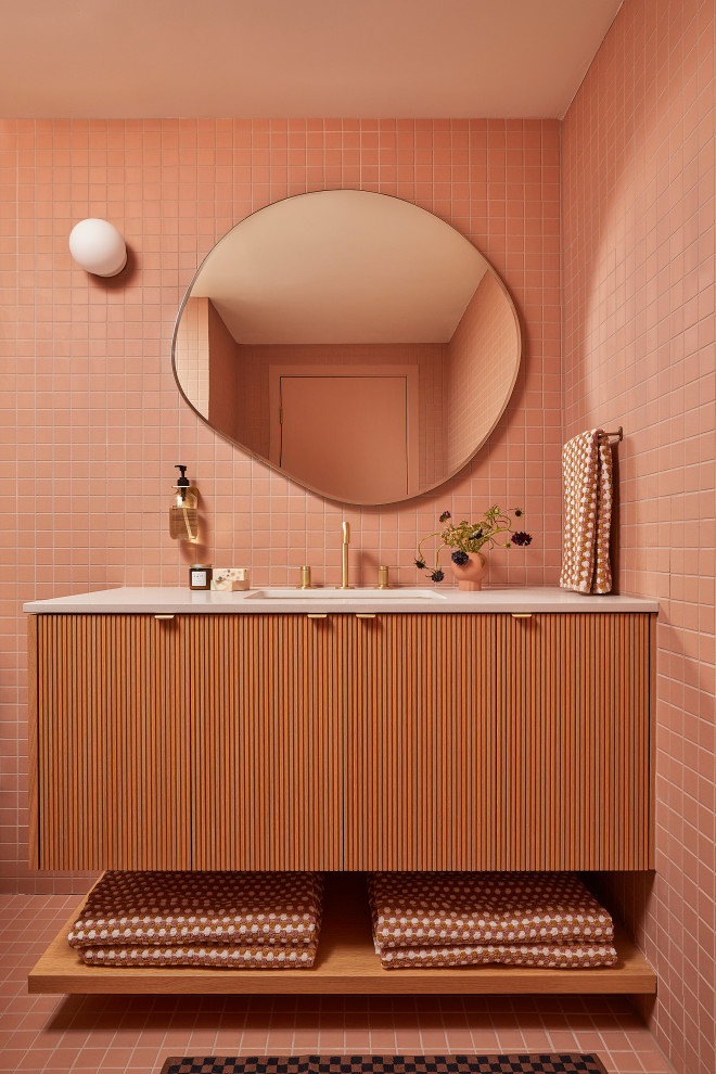 Small midcentury bathroom in San Francisco with light wood cabinets, a curbless shower, a one-piece toilet, pink tile, ceramic tile, pink walls, ceramic floors, an undermount sink, engineered quartz benchtops, pink floor, a hinged shower door, grey benchtops, a niche, a single vanity and a floating vanity.
