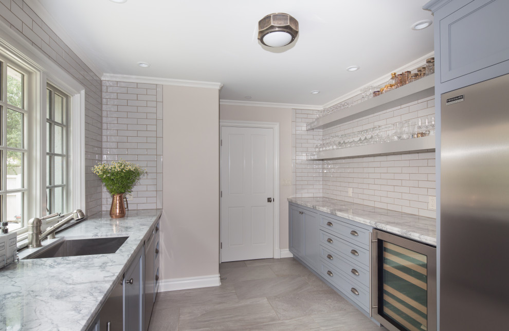 Inspiration for a large transitional u-shaped porcelain tile and gray floor enclosed kitchen remodel in Los Angeles with a drop-in sink, shaker cabinets, quartzite countertops, white backsplash, ceramic backsplash, stainless steel appliances, an island and gray countertops