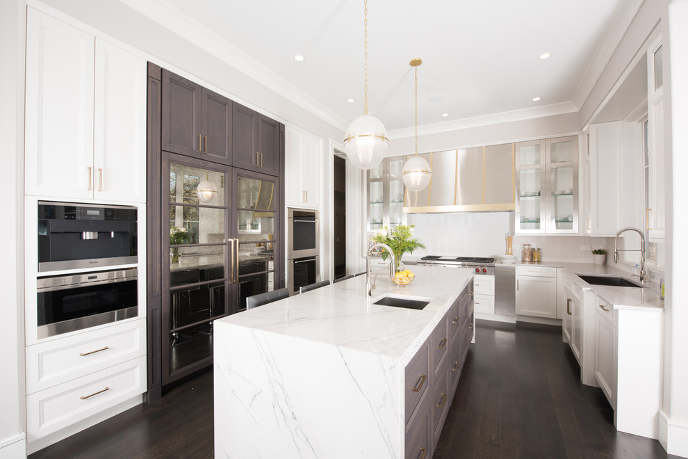 This is an example of a large transitional eat-in kitchen in Chicago with an undermount sink, recessed-panel cabinets, white cabinets, quartzite benchtops, white splashback, glass tile splashback, panelled appliances, dark hardwood floors, with island and brown floor.
