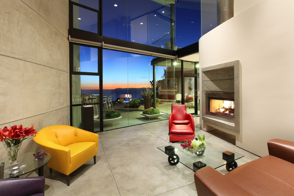 Inspiration for a tropical living room in Orange County with a concrete fireplace surround and concrete floors.