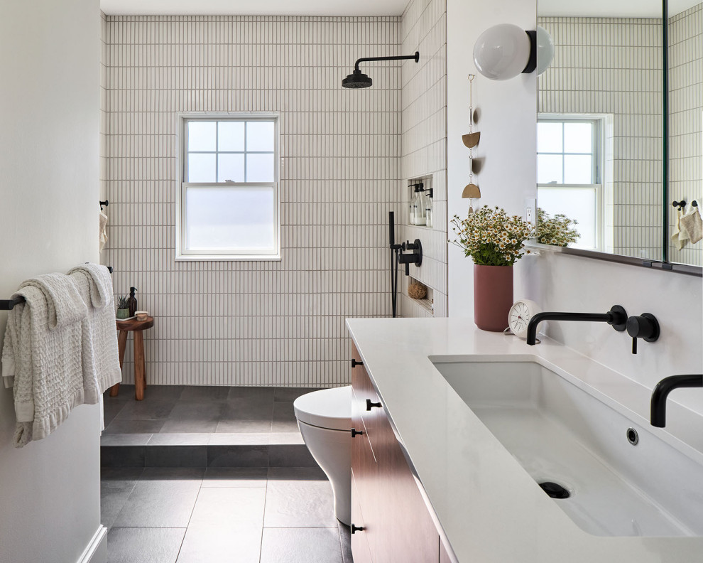Idéer för ett mellanstort retro vit badrum, med släta luckor, skåp i mellenmörkt trä, en dusch i en alkov, en toalettstol med hel cisternkåpa, vit kakel, keramikplattor, vita väggar, klinkergolv i porslin, ett avlångt handfat, bänkskiva i kvarts, grått golv och dusch med duschdraperi