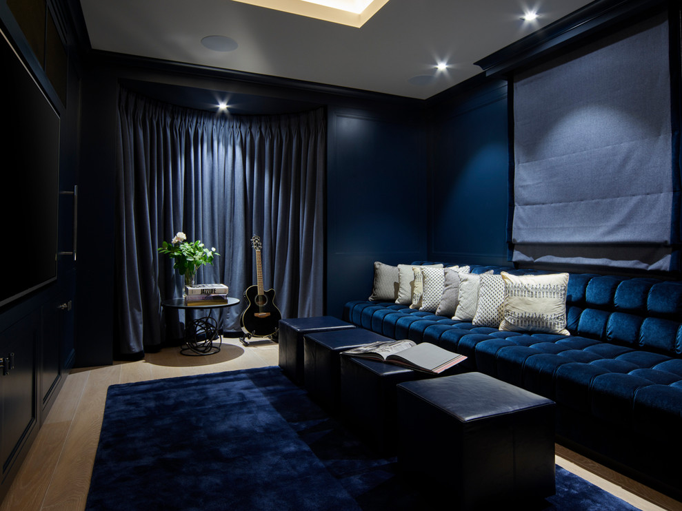 Mid-sized contemporary enclosed home theatre in London with blue walls, light hardwood floors, a built-in media wall and beige floor.