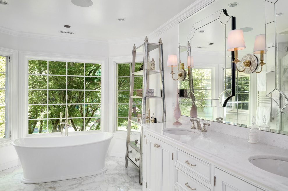 Inspiration for a large traditional master bathroom in Seattle with white cabinets, a freestanding tub, an alcove shower, a two-piece toilet, white tile, blue walls, an undermount sink, marble benchtops, beige floor, a hinged shower door, white benchtops, an enclosed toilet, a double vanity, a built-in vanity and beaded inset cabinets.