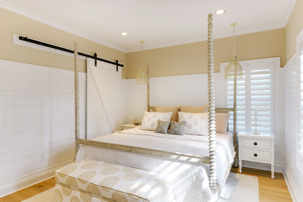 This is an example of a beach style master bedroom in Other with beige walls and light hardwood floors.