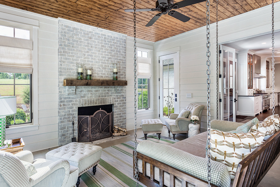 Large country sunroom in Other with a wood stove, a brick fireplace surround, a standard ceiling, concrete floors and grey floor.