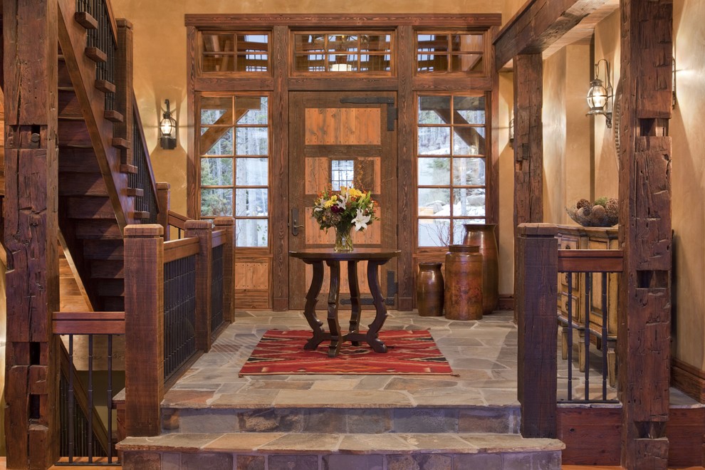 This is an example of a mid-sized country foyer in Other with beige walls, a single front door, a dark wood front door, slate floors and multi-coloured floor.