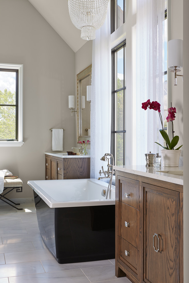 Design ideas for an expansive eclectic master bathroom in Minneapolis with raised-panel cabinets, dark wood cabinets, a freestanding tub, a double shower, a one-piece toilet, beige walls, marble floors, an undermount sink, granite benchtops, grey floor and a hinged shower door.