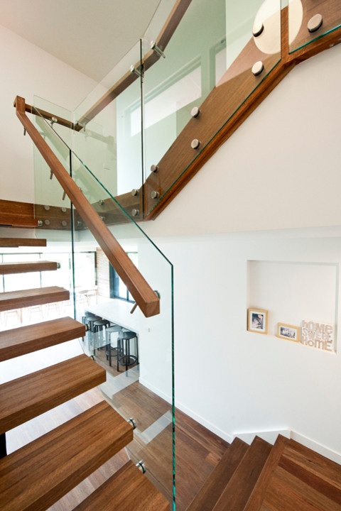 This is an example of a large modern wood l-shaped staircase in Melbourne with open risers.