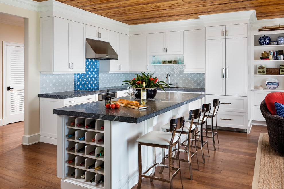 Mid-sized beach style l-shaped medium tone wood floor and brown floor open concept kitchen photo in Miami with an undermount sink, white cabinets, marble countertops, gray backsplash, ceramic backsplash, stainless steel appliances, an island and shaker cabinets