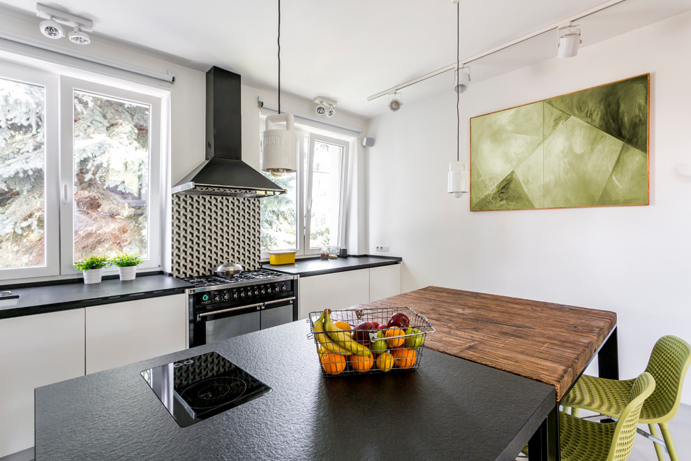 This is an example of a mid-sized contemporary l-shaped eat-in kitchen in Los Angeles with a drop-in sink, flat-panel cabinets, white cabinets, multi-coloured splashback, porcelain splashback, black appliances, multiple islands and beige floor.
