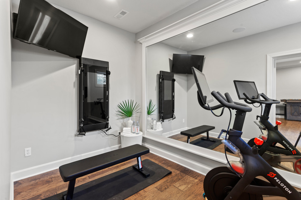Großer Klassischer Fitnessraum mit grauer Wandfarbe, hellem Holzboden und braunem Boden in Kansas City