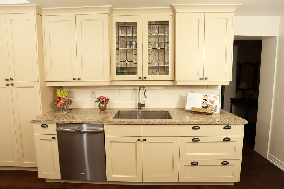 Inspiration for a small transitional galley medium tone wood floor and brown floor enclosed kitchen remodel in Toronto with a double-bowl sink, shaker cabinets, beige cabinets, quartz countertops, beige backsplash, ceramic backsplash, stainless steel appliances and a peninsula