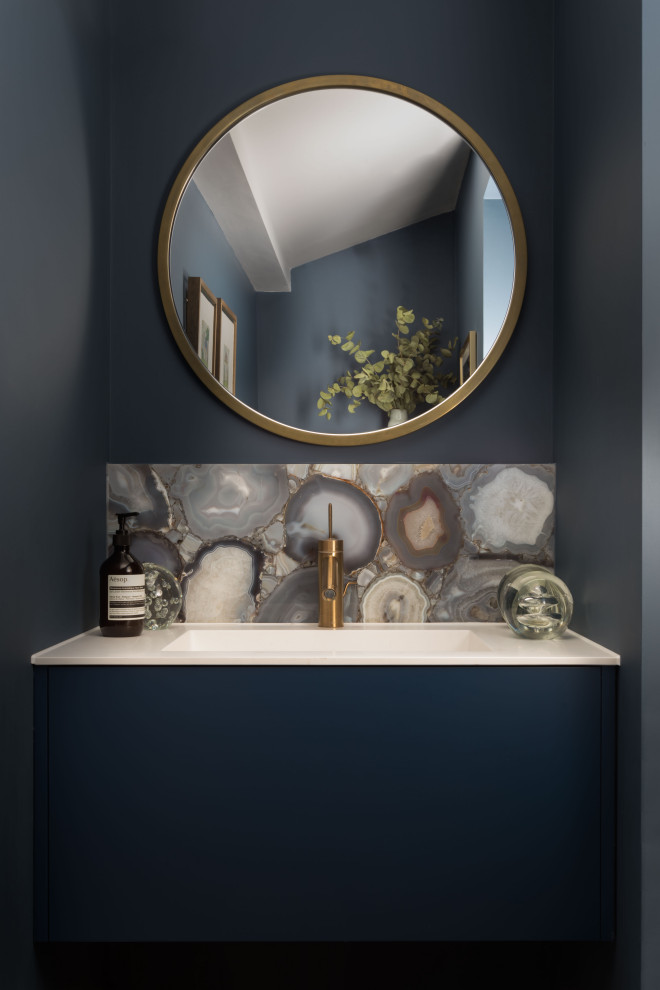 Small contemporary powder room in London with flat-panel cabinets, blue cabinets, multi-coloured tile, grey walls, an undermount sink and white benchtops.