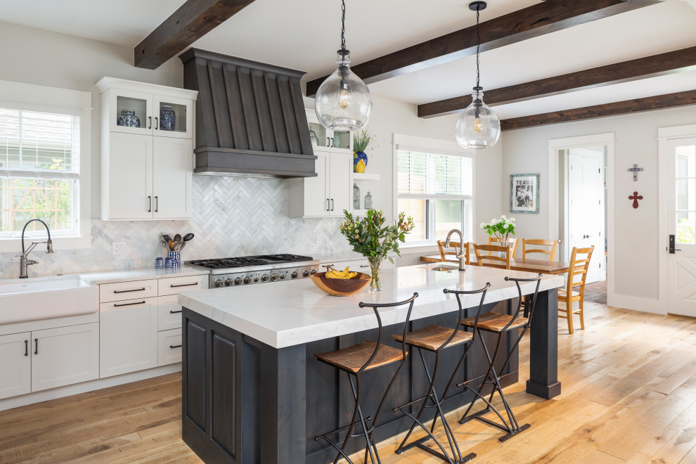 Eat-in kitchen - large country light wood floor and beige floor eat-in kitchen idea in Denver with a farmhouse sink, shaker cabinets, white cabinets, quartzite countertops, white backsplash, stainless steel appliances, an island, white countertops and marble backsplash