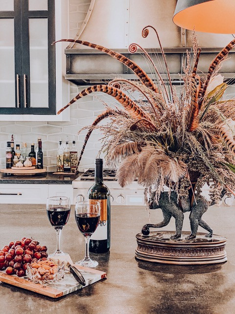 Mid-sized transitional medium tone wood floor and brown floor eat-in kitchen photo with a farmhouse sink, shaker cabinets, white cabinets, soapstone countertops, gray backsplash, porcelain backsplash, stainless steel appliances, an island and black countertops